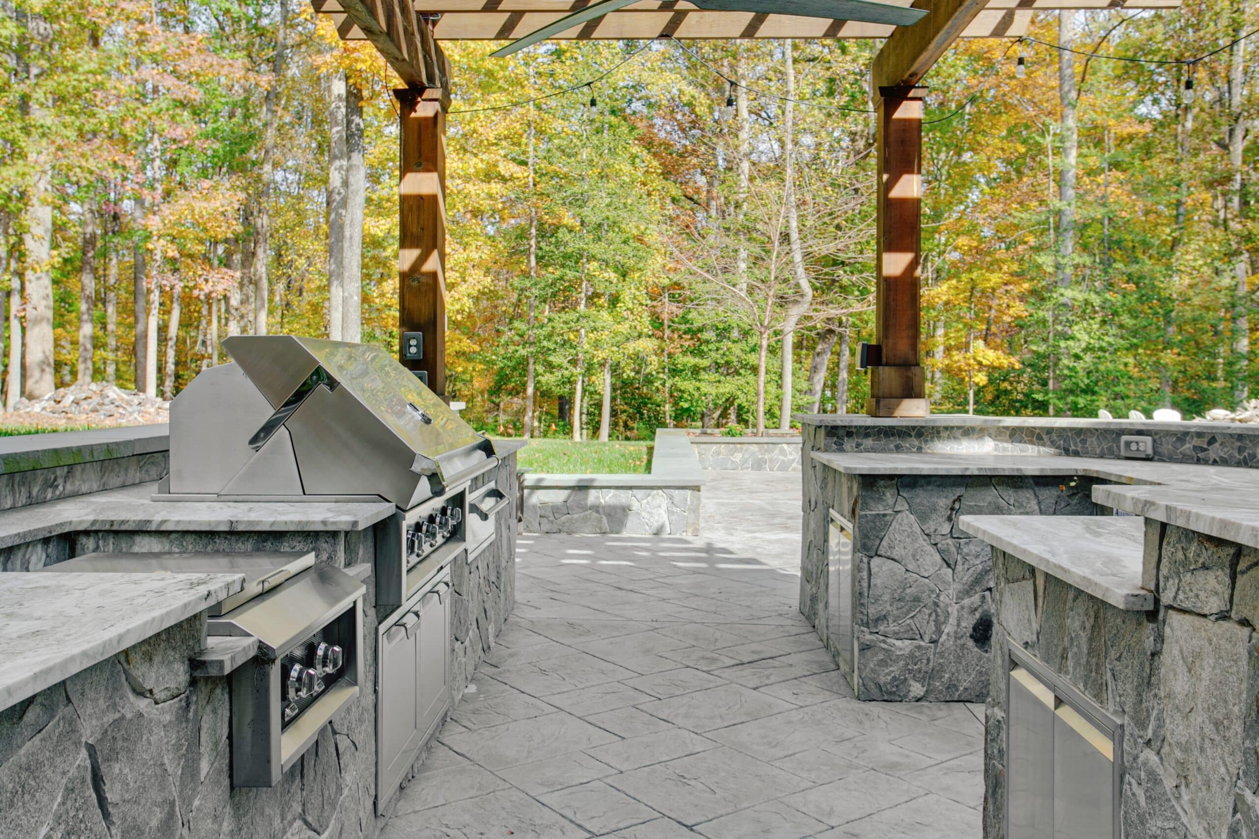 a outdoor kitchen with a pergola and trees in the background